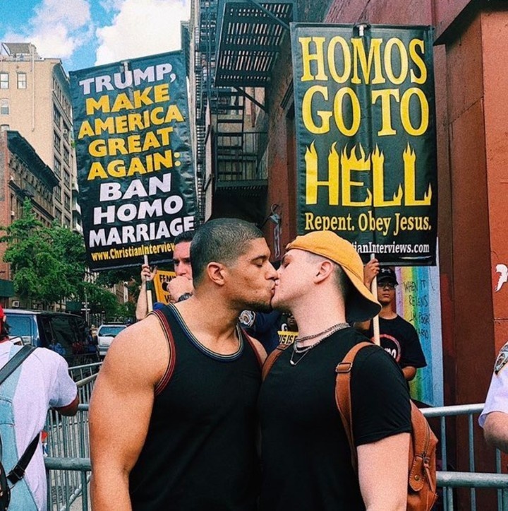 Out wrestler Anthony Bowens took to social media this week to share a photo of himself locking lips with his boyfriend Michael Pavano — but what makes the snap noteworthy is that it takes place in front of a crowd of anti-LGBTQ+ protestors, who are seen holding homophobic signs.⁠
⁠
"Trump make America great again: ban homo marriage," one sign in all-caps reads. "Homos go to hell. Repent. Obey Jesus," another sign says.⁠
⁠
Captioning the pic on Twitter, Bowens wrote "#Standup to hate," tagging Pavano, GLAAD, and the Human Rights Campaign. Sharing the same post on Instagram, Pavano, a YouTuber, commented "I love you forever & always."⁠
⁠
Bowens came out in 2017 as bisexual and later came out as gay and often speaks out in support of LGBTQ+ causes. In 2019 he was interviewed by Sports Illustrated, opening up about how he represents the LGBTQ+ community.⁠
⁠
Tap link in bio to continue on @EDGEmedianetwork ????⁠
⁠
?: Anthony Bowens & Michael Pavano / Twitter