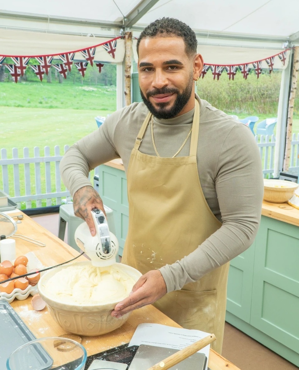 His name is Sandro Farmhouaw and he's an out, tatted and bearded, 30-year old nanny living in London. He's also the break-out star of 2022 edition of Netflix's "The Great British Bake Off."And is in a relationship, having introduced his boyfriend in one episode. It didn't take long for fans to call him "cake daddy" and "the great British baking snack." While one fan wrote they "can't wait for Bred Week" — with intentional misspelling. On the show's website, he is described as being born in Angola, but came to London to feel the war in his country with his mother. He made an impression on the show's opening episode by showing off his fitness routine. Trained in boxing and ballet, he says he turned to baking as a form of therapy after his dad died when he was 21. "Now, he lives and breathes it, and is often found rustling up bakes in a relaxed vibe with the telly on, or running virtual baking classes for children with autism." Working with children is important for Farmhouse, whose name suggests a vision of bucolic country residence. Working with the group Social Ark, prompted Sandro to create baking and cake decorating workshops for autistic children. "Social Ark has introduced me to real community leadership. I am passionate about creative baking and supporting children and young people with special needs to flourish. I'm full of aspirations and really looking forward to the future, being part of Social Ark and wherever my baking journey takes me."⁠
⁠
Tap link in bio for more on @EDGEmedianetwork ⁠
????⁠
?: @sandrosbakes