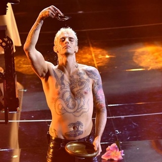 The Vatican and an Italian Catholic bishop this week protested a performance at Italy's Sanremo music festival that featured a "profane" faux baptism on stage, lamenting in particular that it was broadcast on public television. On the opening night of the annual song contest, a tattooed, bare-chested and barefoot singer named Achille Lauro gyrated and grabbed his crotch as he sang "Domenica" ("Sunday"), backed up by singers from the Harlem Gospel Choir. He finished by kneeling on stage, hands clasped in front of him as if in prayer, and poured water from a bowl over his forehead. Sanremo Bishop Antonio Suetta said the performance contained "words, attitudes and gestures that are not just offensive to religion, but to human dignity." Lauro said in comments on his Instagram feed, which has 1.7 million followers, that he wanted to give his opening night performance at Sanremo to his mother as a birthday present. "Mothers are divine beings, they give us life everyday, today in a new beginning, I give you my baptism," he wrote in a post that had over 2,000 comments.⁠
⁠
Tap link in bio to continue on @EDGEmedianetwork⁠
???????⁠
?: ACHILLE LAURO® / @achilleidol / AP